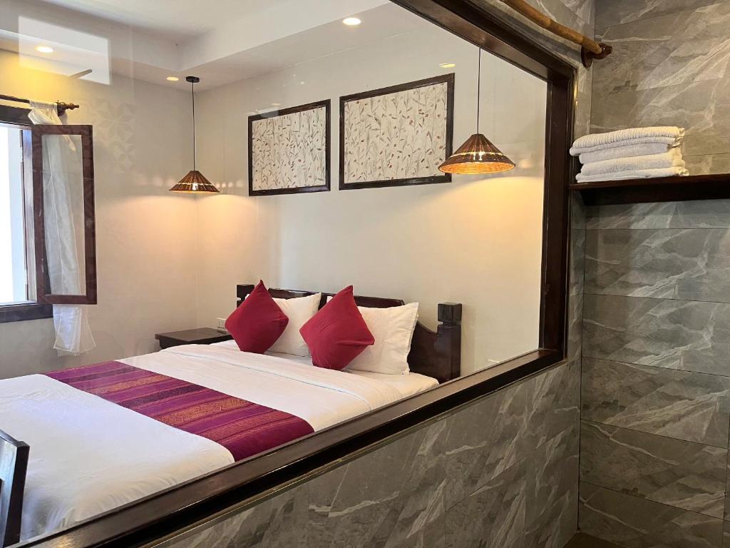 a bedroom with a large bed with red pillows at Villa Namkhan Heritage in Luang Prabang
