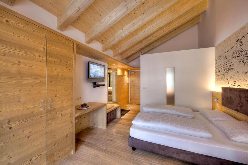 a bedroom with a bed and wooden walls at Hotel Rezia in La Villa