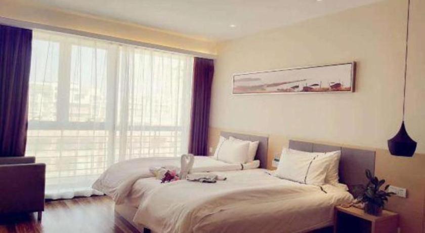 a bedroom with a large white bed in front of a window at City Comfort Inn Zhenjiang Jurong Shimao in Jurong