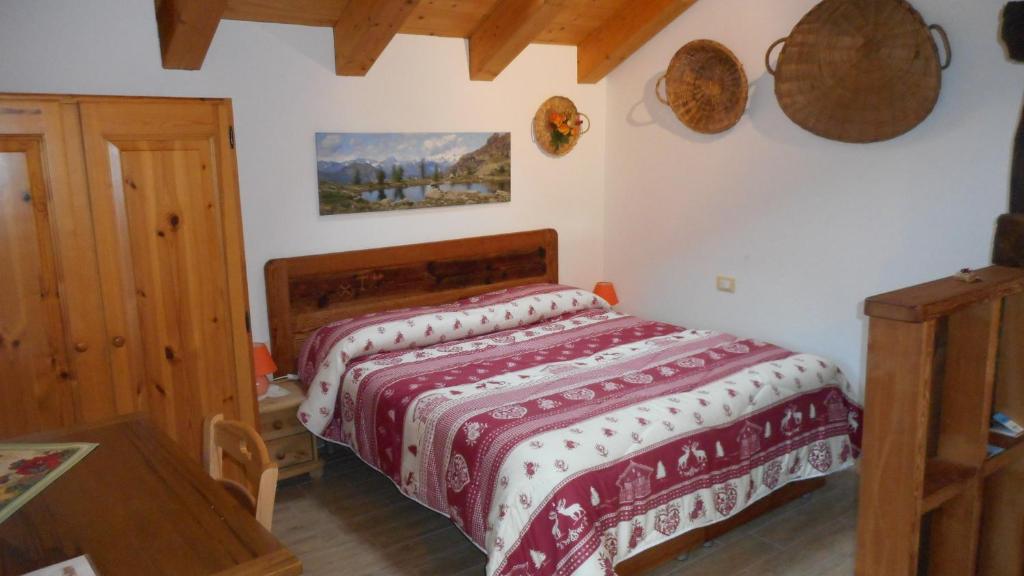Schlafzimmer mit einem Bett mit einer roten und weißen Decke in der Unterkunft La Luge in Saint-Christophe