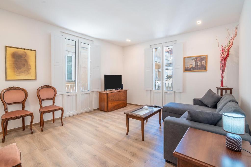 a living room with a couch and chairs and a tv at Ognissanti Holiday House in Ragusa