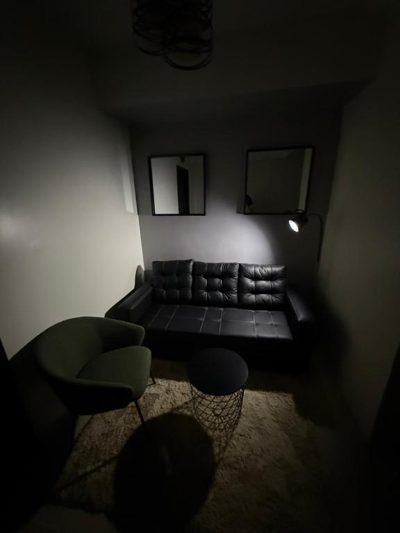 un salon sombre avec un canapé et une chaise dans l'établissement NFr, à Manille