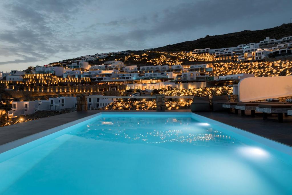 a pool with a view of a city at night at Cova Mykonos Suites in Elia Beach