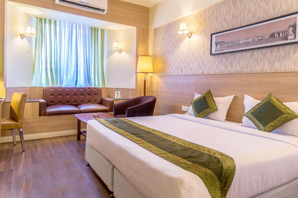 a hotel room with a large bed and a chair at Treebo Tryst Grand Emerald in Pune