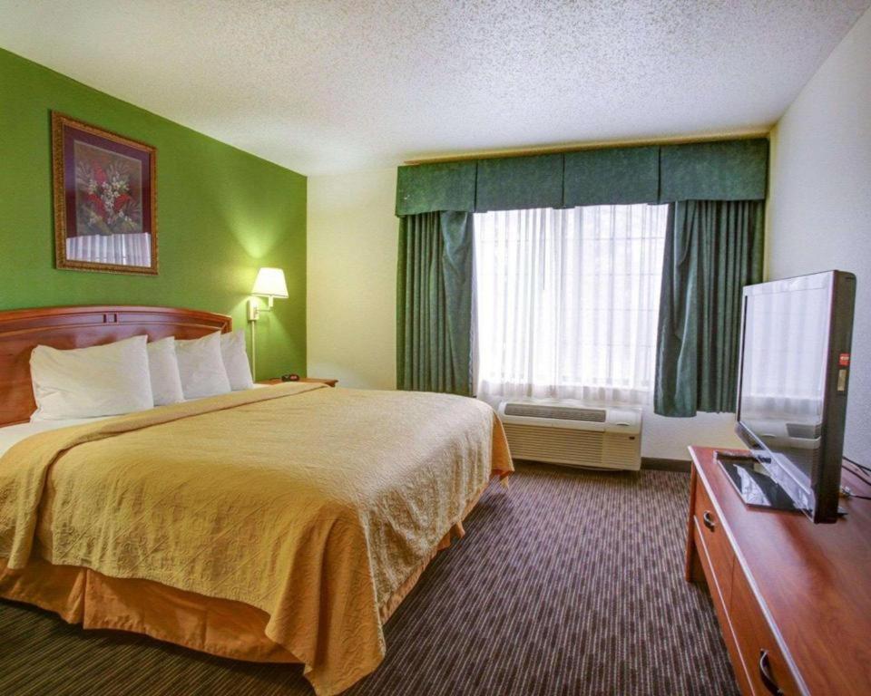 a hotel room with a bed and a flat screen tv at Quality Inn & Suites Airport in Austin