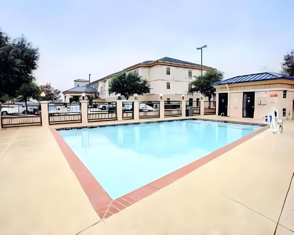 a large swimming pool with blue water in front of a building at Quality Inn & Suites Airport in Austin