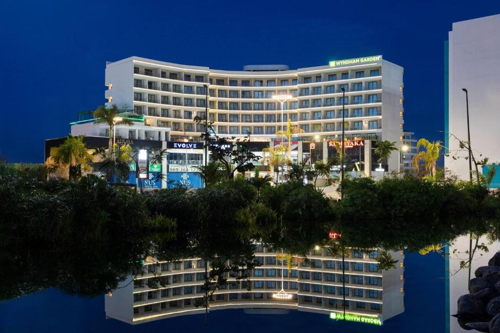 a hotel building with a reflection in the water at Wyndham Garden Mazatlan Marina in Mazatlán