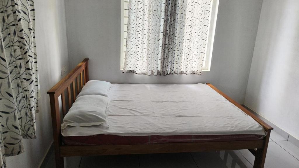 a small bed in a room with two windows at Vasudha Eco Homestay in Paithalmala