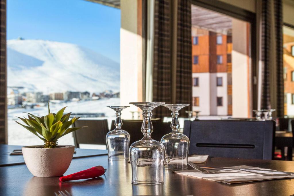a table with two wine glasses and a plant on it at Hôtel Club mmv Les Bergers **** in L'Alpe-d'Huez
