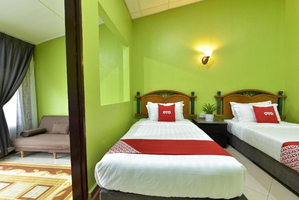 two beds in a room with green walls at OYO 90818 Cemara Puri Resort & Spa in Kampong Pantai Batu Hitam
