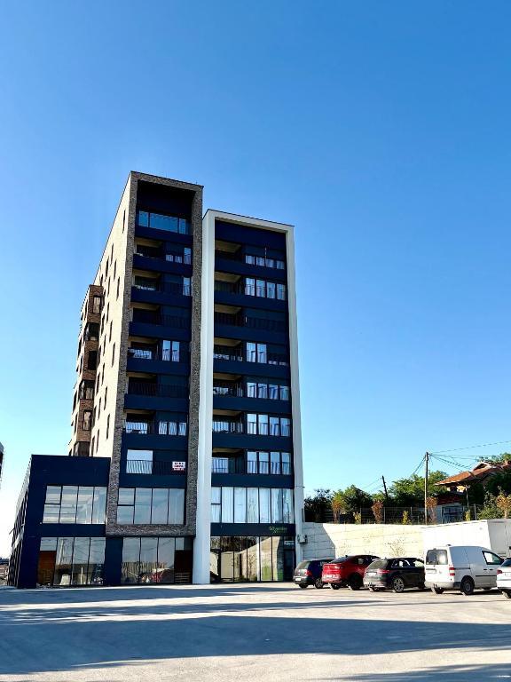 a tall building with cars parked in front of it at Tians Apartment in Prishtinë