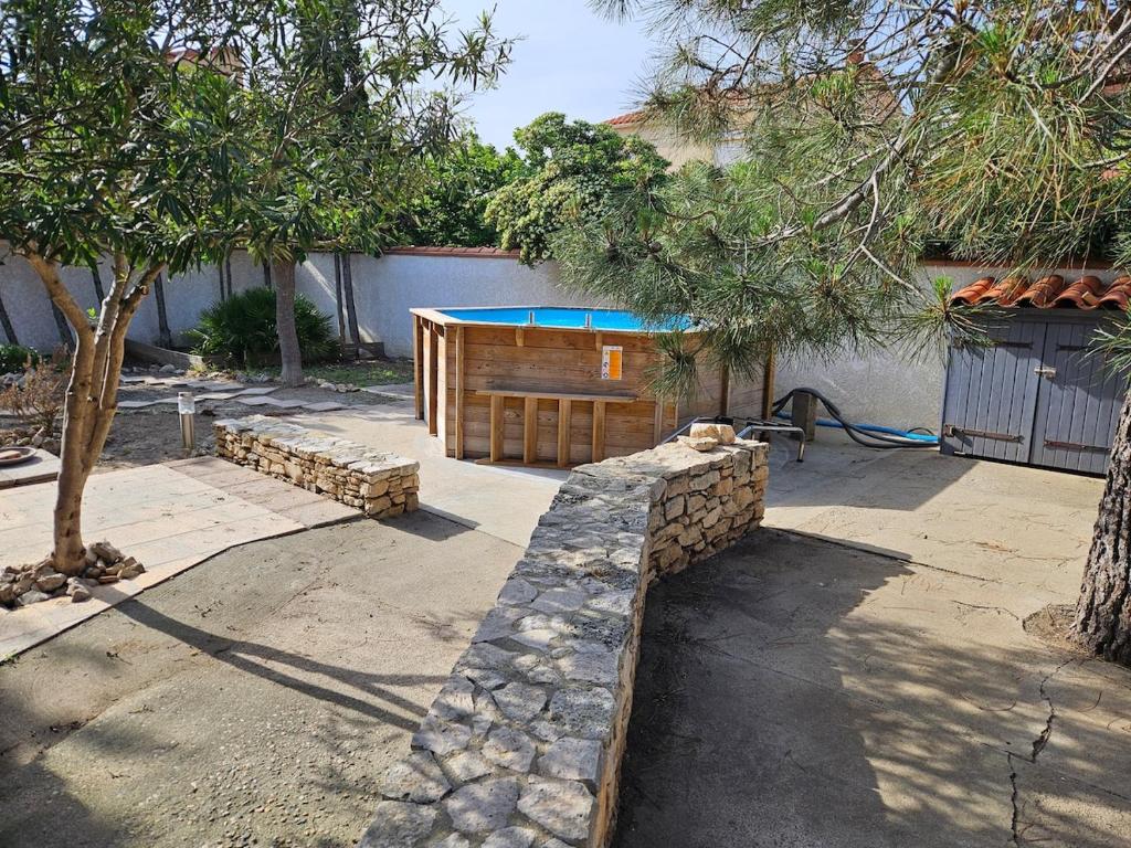 une arrière-cour avec une piscine et un mur en pierre dans l'établissement Maison LE BARCARES à 450m de la plage, au Barcarès