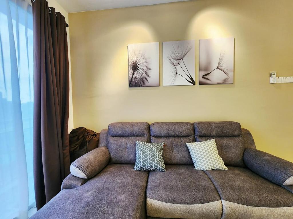 a living room with a couch and three paintings on the wall at Malacca 3 bedroom Seri Serindit 07 in Melaka
