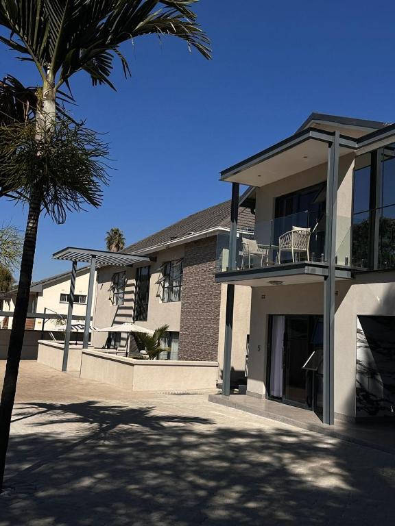 a building with a palm tree in front of it at The Mendel Boutique Residence in Harare