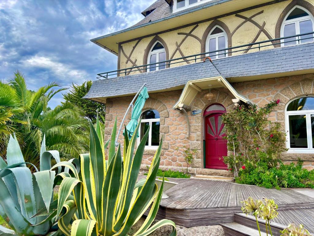 une maison en briques avec une porte rouge et quelques plantes dans l'établissement La Pagode, à Trégastel
