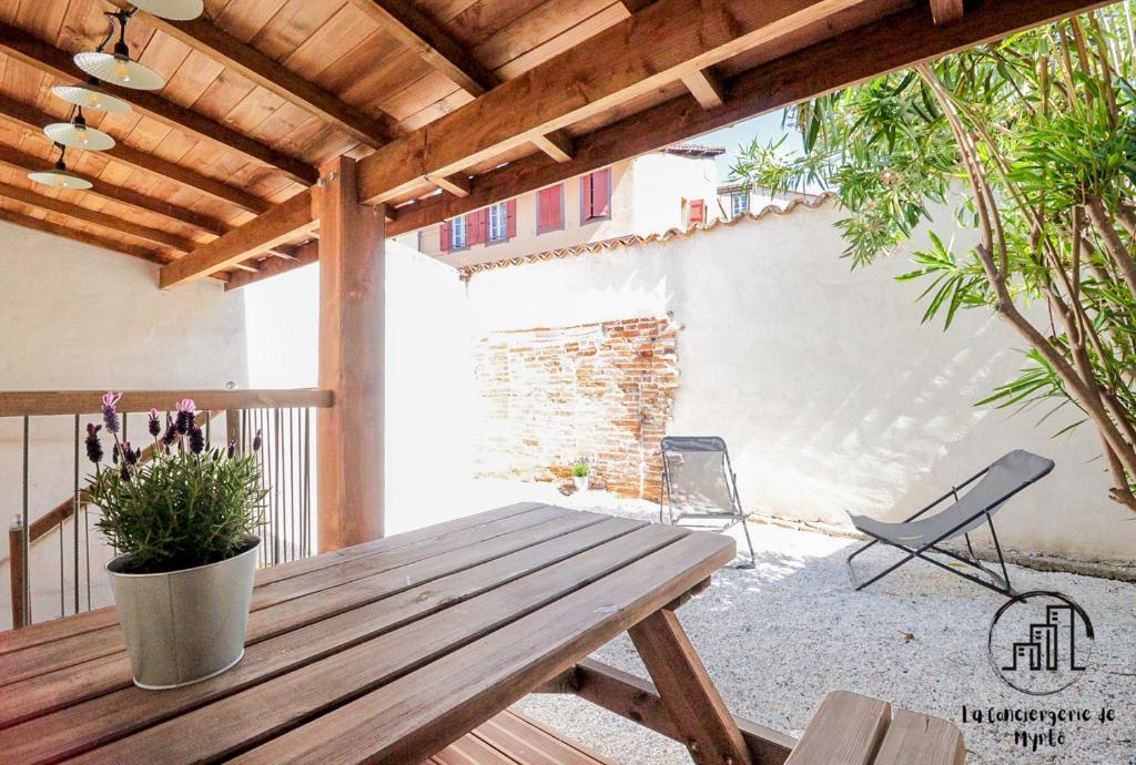 a patio with a wooden picnic table and chairs at Le Nordet Vert in Albi