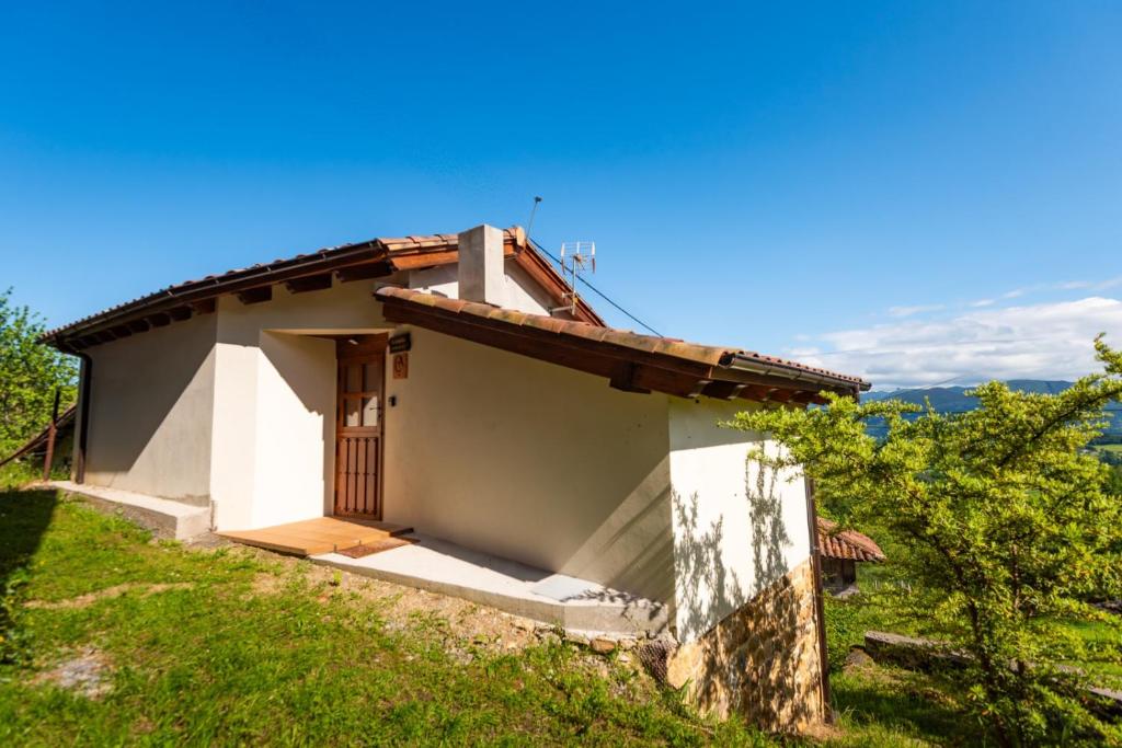 una pequeña casa blanca con una puerta en una colina en La Cabaña, en Robledo