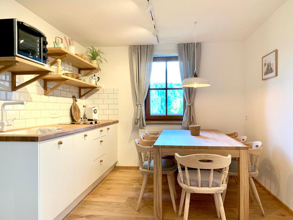 a kitchen with a table and a small kitchen with white cabinets at VOM REITER, Ferienwohnung am Bauernhof mit Bergblick und privater Infrarotkabine, Inklusive Sommercard in Schladming