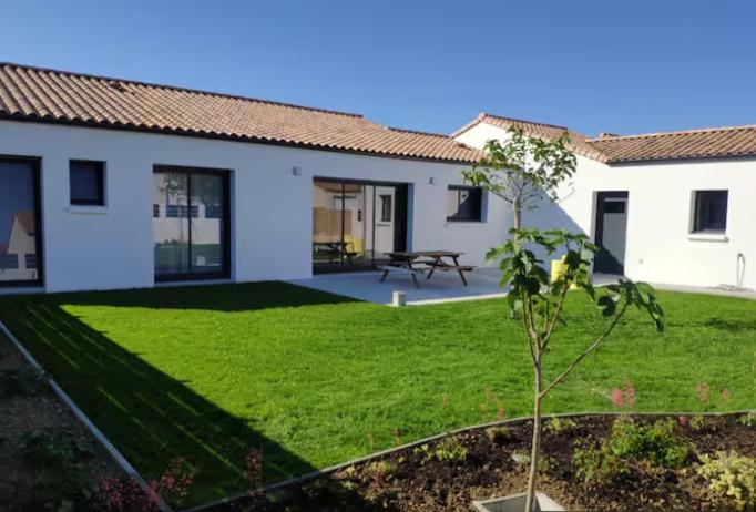 une maison avec une pelouse verte devant elle dans l'établissement Maison neuve spacieuse - 6 pers - proche St Gilles, à Givrand