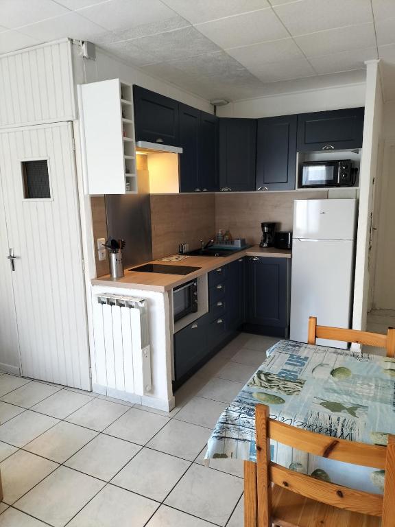 La cuisine est équipée de placards noirs et d'un four avec plaques de cuisson blanches. dans l'établissement Paisible appartement à deux pas de la Plage, à Saint-Hilaire-de-Riez