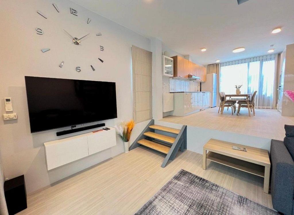 ein Wohnzimmer mit einer großen Uhr an der Wand in der Unterkunft Discover your sanctuary at this townhouse in Plai Laem