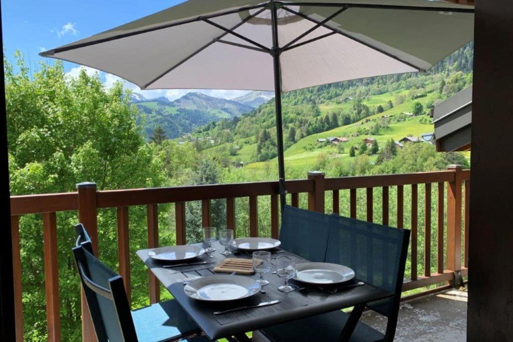 - une table avec des verres et un parasol sur le balcon dans l'établissement Cosy apartment with balcony and mountain view, à Flumet
