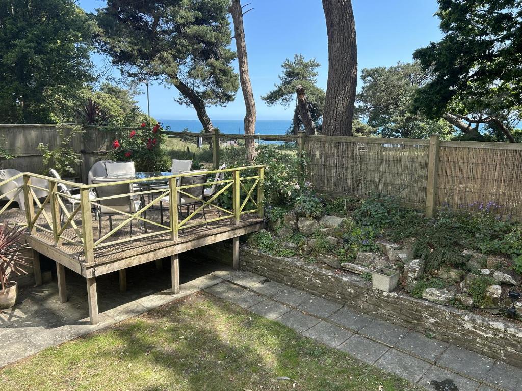a wooden bench in a garden with a fence at Hoppapill House in Bournemouth