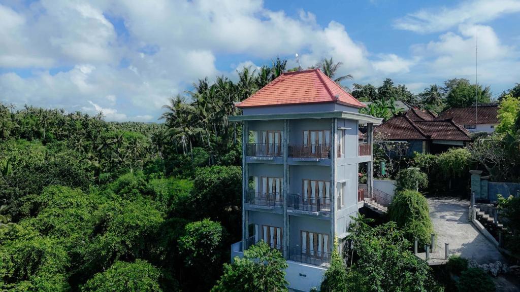 un bâtiment avec un toit rouge dans la forêt dans l'établissement Atuh Galaxy Cottage, à Nusa Penida