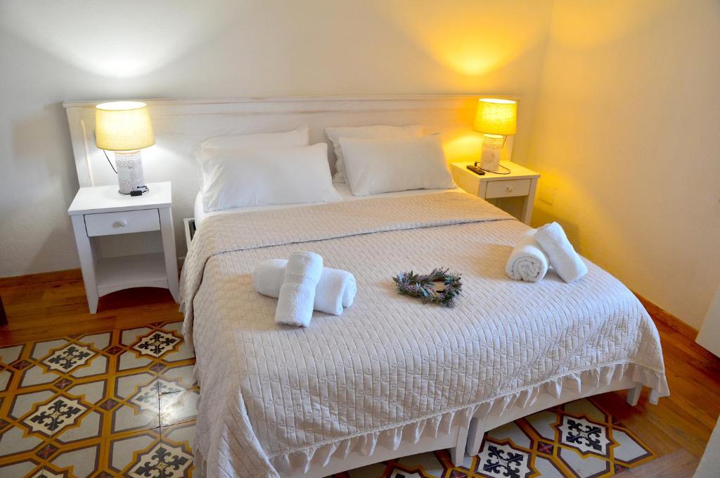 1 dormitorio con 1 cama con toallas y 2 lámparas en L'araucaria Le Camere, en Riola Sardo