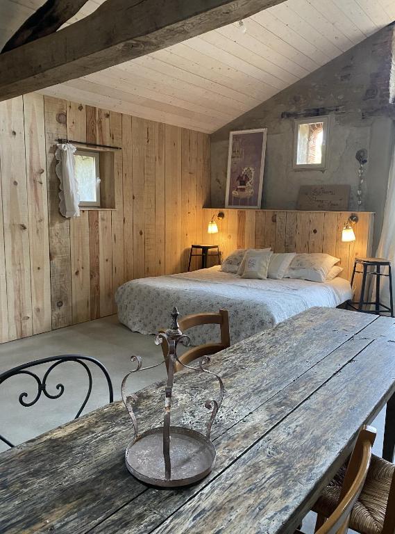 une chambre avec un lit et une table en bois dans l'établissement Le logis de la Grange aux Gîtes de l'Etang des Noues,, à Cholet