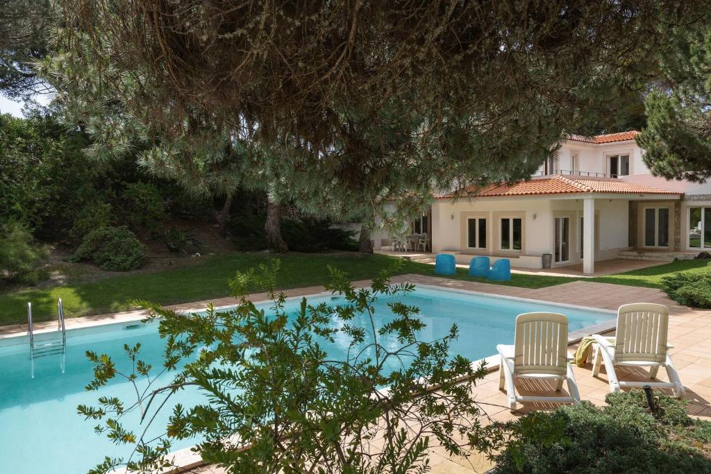 une piscine avec deux chaises et une maison dans l'établissement Oasis Pool Villa - Praia D'El Rey Golf Resort, à Palaios