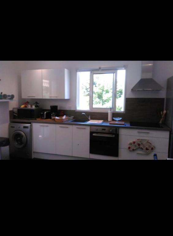 une cuisine avec des armoires blanches et une fenêtre dans l'établissement Charmant logement, à Pianottoli-Caldarello