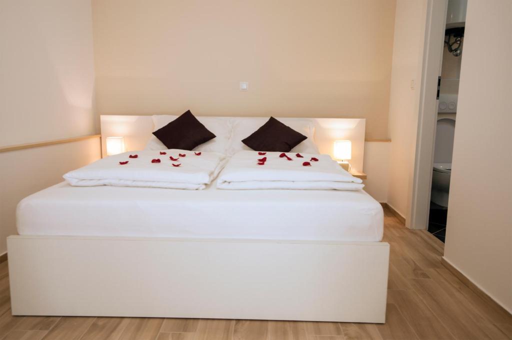 ein weißes Bett mit roten Rosen darüber in der Unterkunft Guest House Bulevar in Zadar