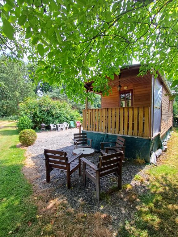 eine Gruppe von Bänken, die außerhalb einer Kabine sitzen in der Unterkunft La Roulotte Authentique au pays de George Sand avec piscine in Mouhers