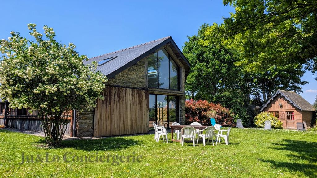 un gîte avec une table et des chaises dans la cour dans l'établissement Authentique Piscine Couverte Chauffée Vue Nature, à Guéméné-Penfao