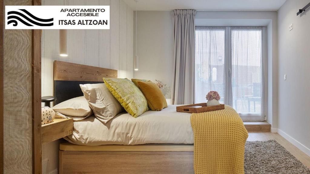 サラウツにあるALTZOAN apartamentos Boutique & Parkingの黄色い枕と窓のあるベッドのある寝室