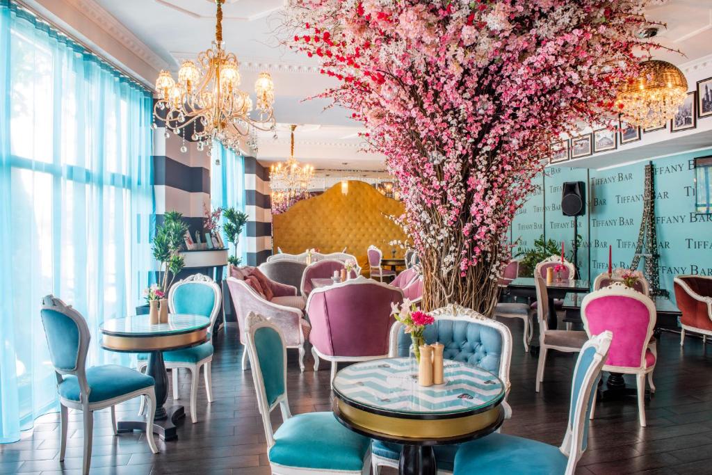 a restaurant with tables and chairs and pink flowers at River Side Hotel Tbilisi in Tbilisi City