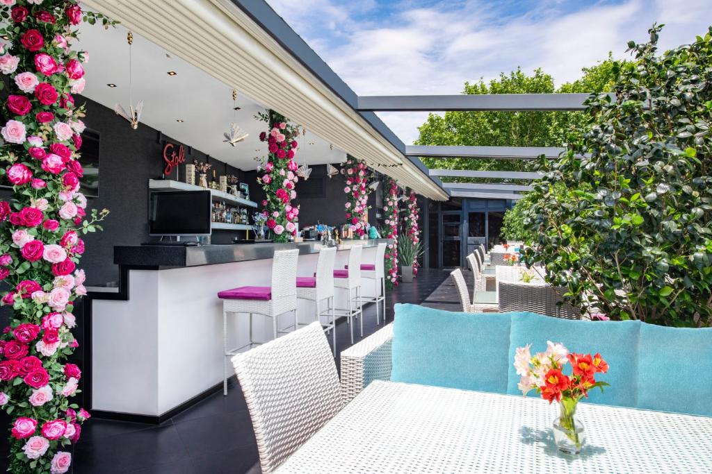 a patio with white tables and chairs and flowers at River Side Hotel Tbilisi in Tbilisi City