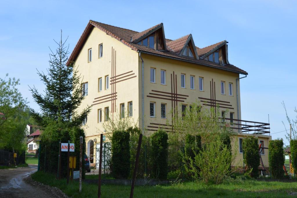 a large yellow building with a tiled roof at Pensiunea Ando in Bran