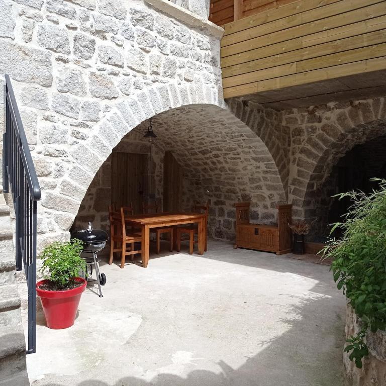 d'une terrasse avec une table en bois et un mur en pierre. dans l'établissement Gîte les Chapélétas au cœur de l'Ardeche, à Saint Alban Auriolles
