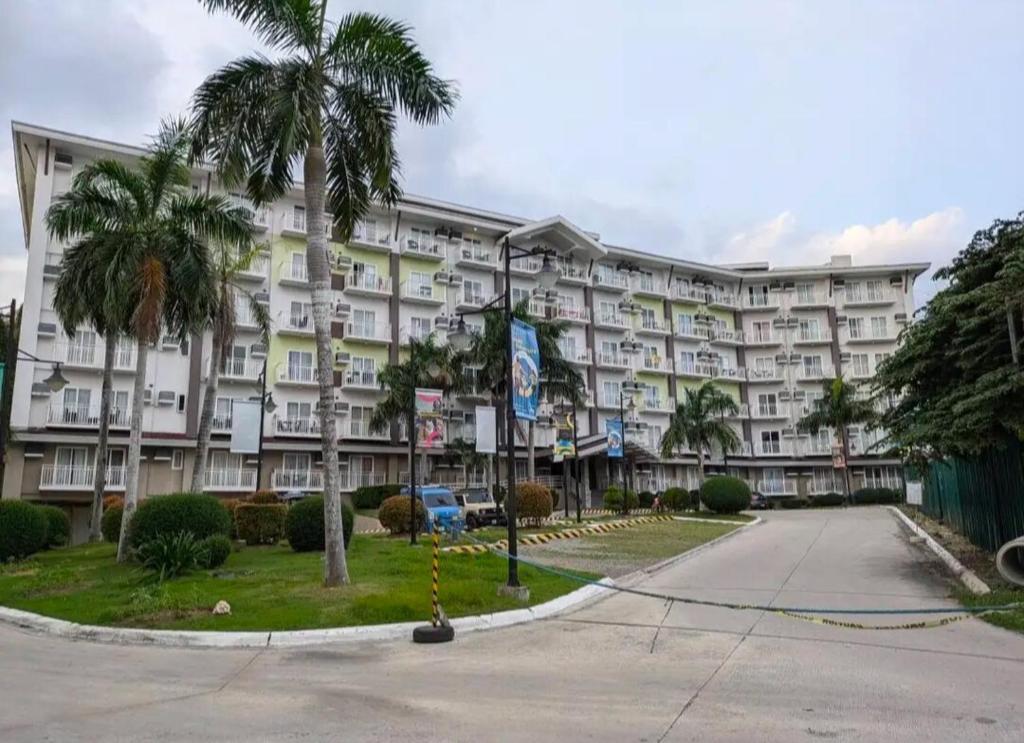 Un gran edificio con palmeras delante. en Rest and Fly Luxurious Budget Stay with Pool and Gym Hosted by Peter, en Pusok