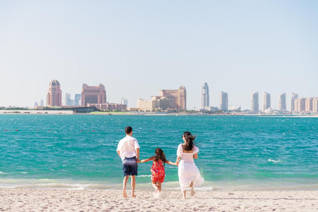 una passeggiata di famiglia sulla spiaggia vicino all'acqua di Millennium Central Doha a Doha
