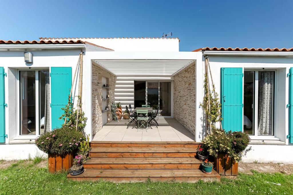 une maison avec une terrasse couverte dotée de volets bleus dans l'établissement Maison Familiale à Grand Village, à Grand-Village-Plage
