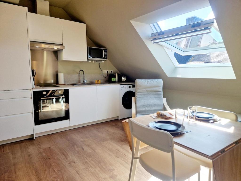 une cuisine avec une table et une cuisine avec une lucarne dans l'établissement L'Ermitage Cosy, à Cherbourg en Cotentin