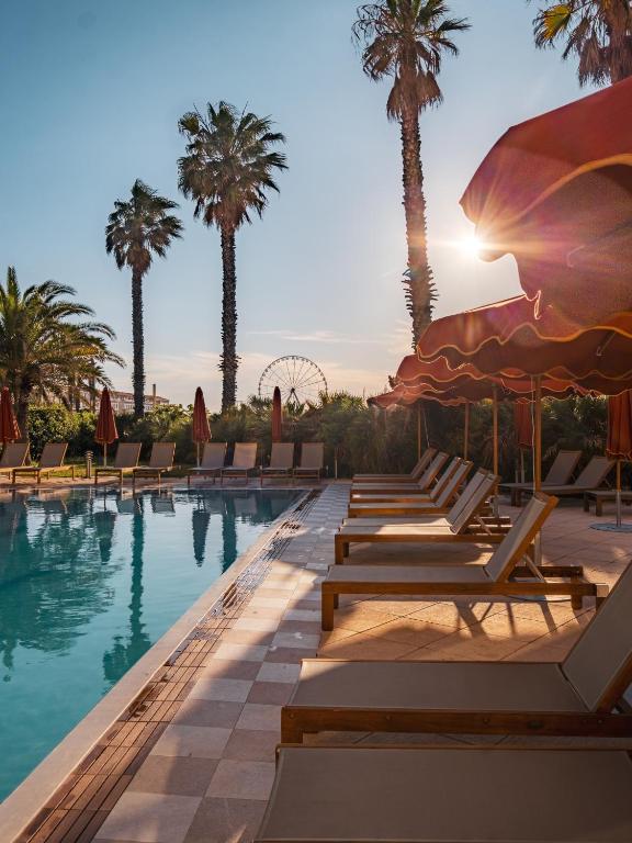 a pool with chaise lounge chairs and palm trees at Hôtel Villa M Marseille in Marseille