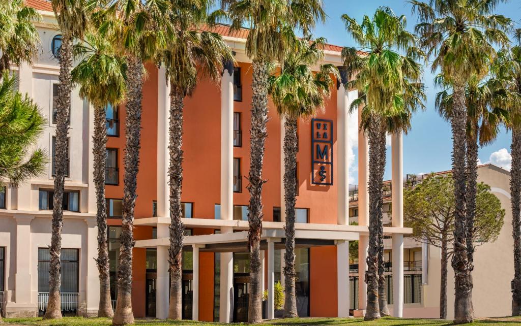 a building with palm trees in front of it at Hôtel Villa M Marseille in Marseille