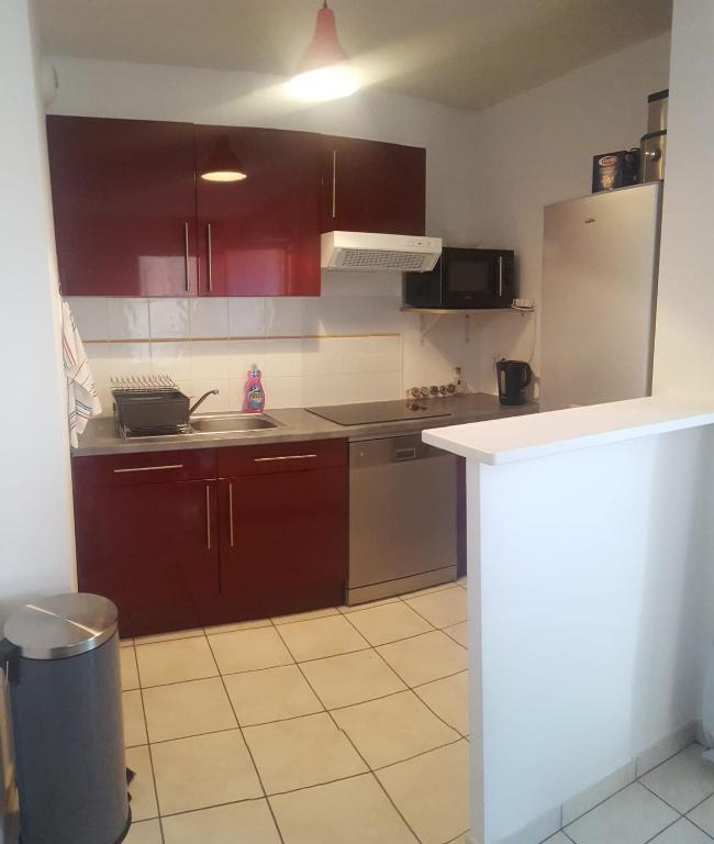 une cuisine avec des armoires rouges et un comptoir blanc dans l'établissement Soleil et Commodité, à La Seyne-sur-Mer