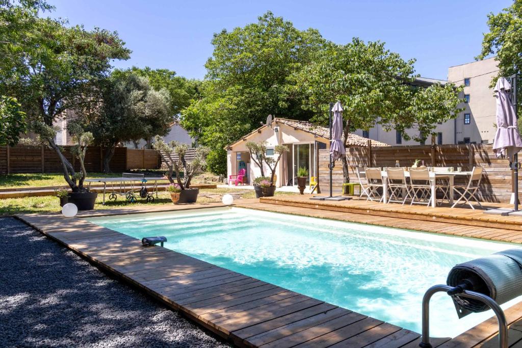 una piscina con terrazza in legno accanto a una casa di Villa Laurens Maison spacieuse avec piscine ad Agde