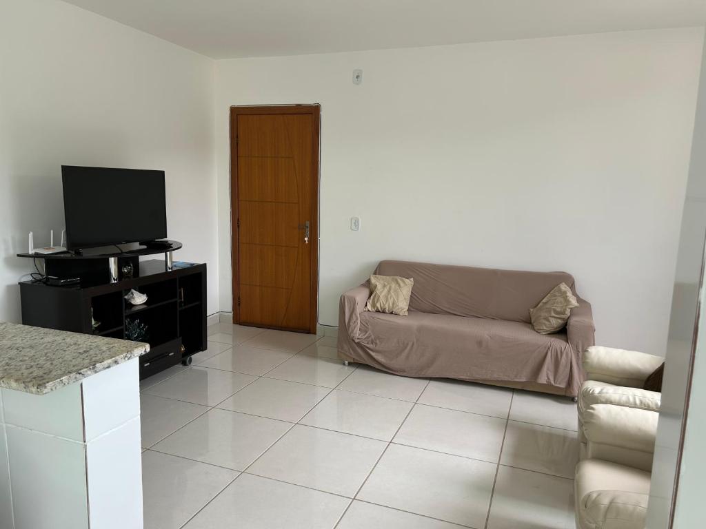 un salon avec un canapé et une télévision dans l'établissement Apto inteiro, novo,2 quartos, silencioso, à Presidente Soares