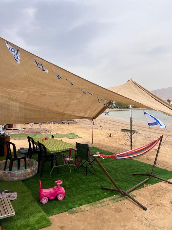 ein Zelt am Strand mit einem Tisch und einem Spielzeugauto in der Unterkunft קרוואן על הים in Eilat